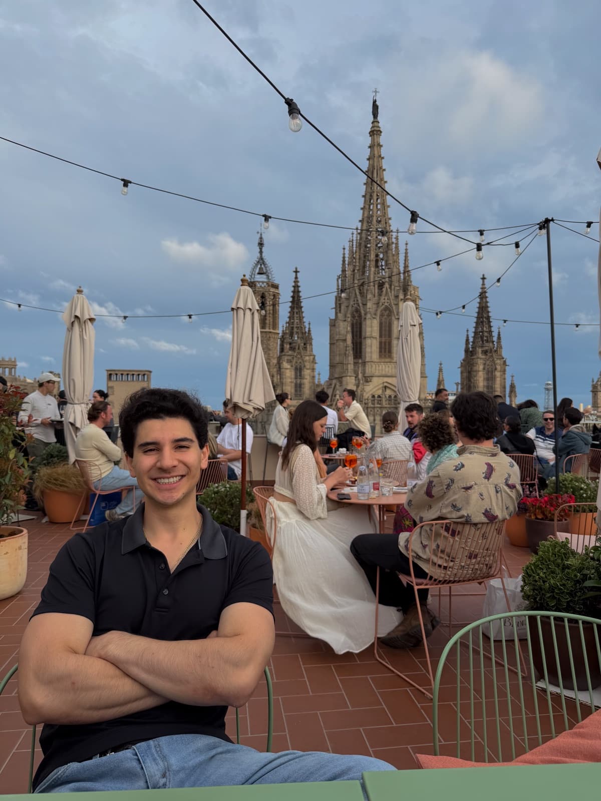 Carter at a rooftop table in Barcelona, arms crossed, smiling